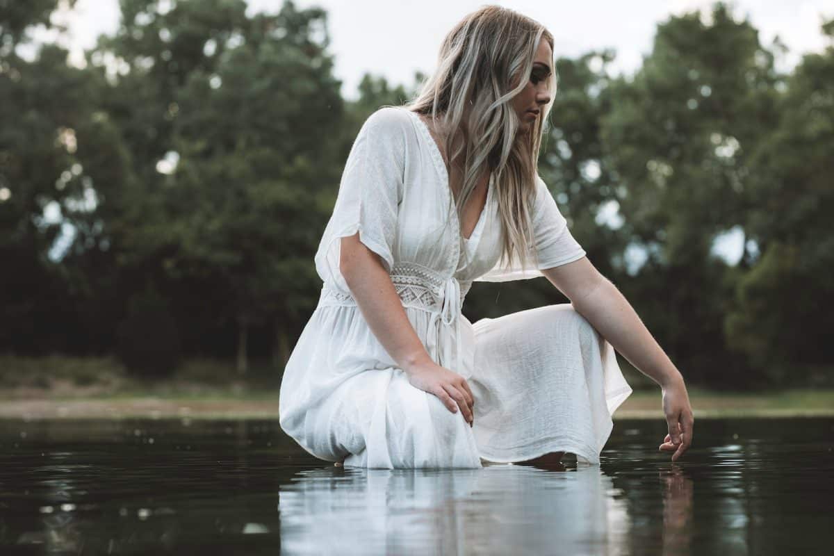 woman in white dress sitting on water during daytime