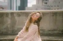 woman in pink long sleeve dress sitting on concrete bench during daytime