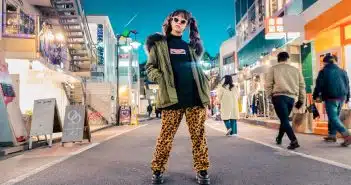 woman in green jacket stands and pose on street