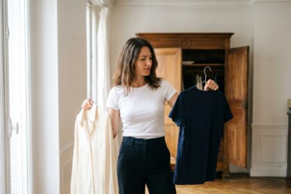 Femme comparant un t-shirt blanc et une blouse chic dans un appartement parisien lumineux
