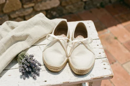 Espadrilles de créateur en toile crème avec semelle en jute posées sur une terrasse provençale en bois patiné, style vue de dessus